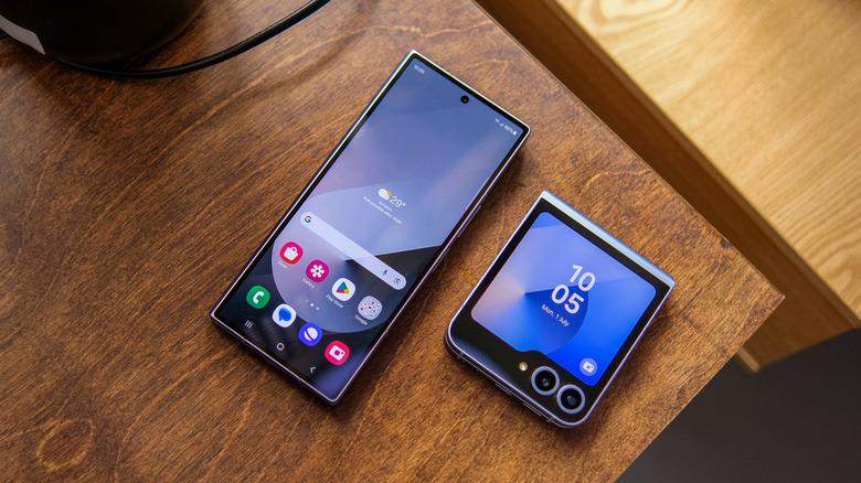 Two Samsung Galaxy Z Flip 6 devices sit next to each other on a bedroom table