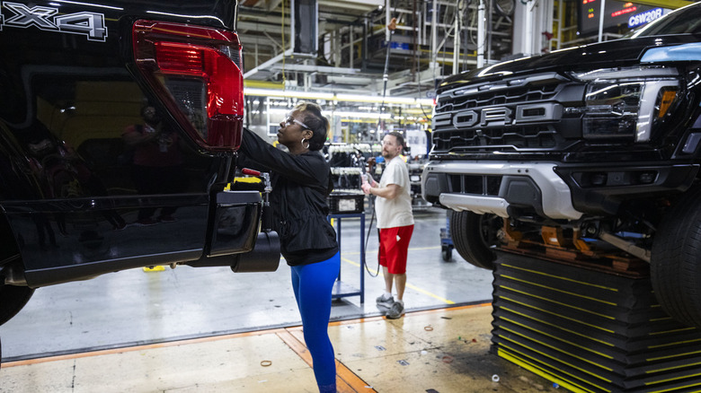 A Ford worker inspects a vehicle on the assembly line