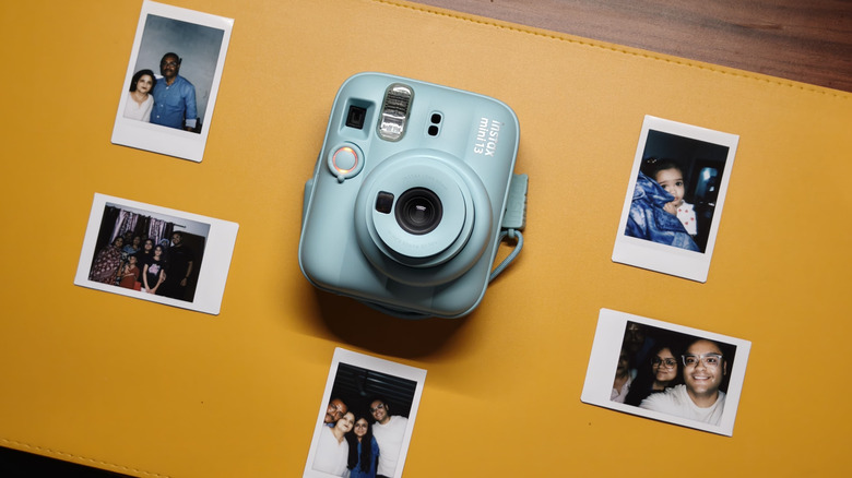 Instax Mini 13 on a table with it's printed images alongside