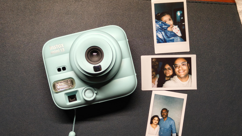 Instax Mini 13 kept on a table with it's printed photos on the right