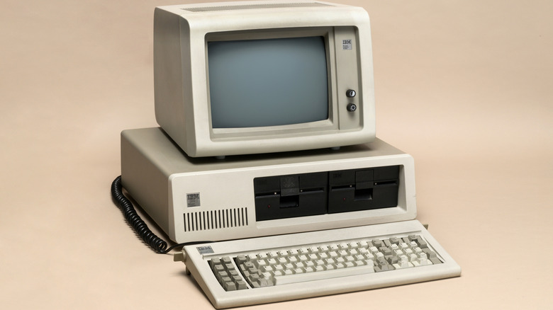 An IBM 5150 PC sits atop a beige infinity drop.