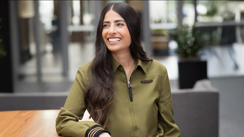 Asha Sharma, EVP and CEO of Microsoft Gaming and Xbox, posing and smiling next to a table