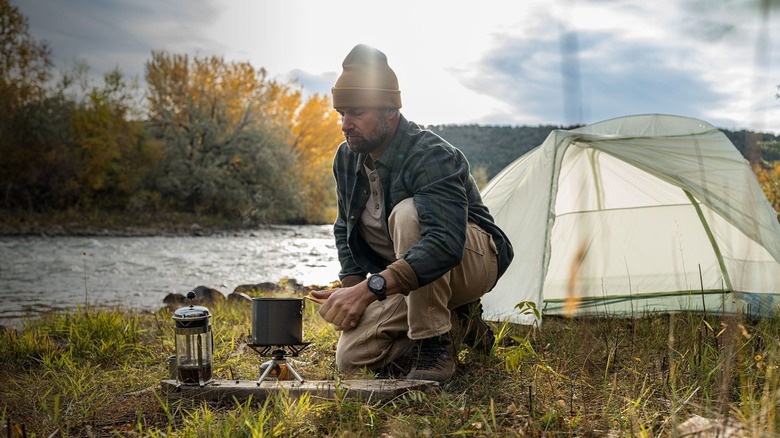 Camper using the Garmin Instinct Solar 3 outdoors while cooking.