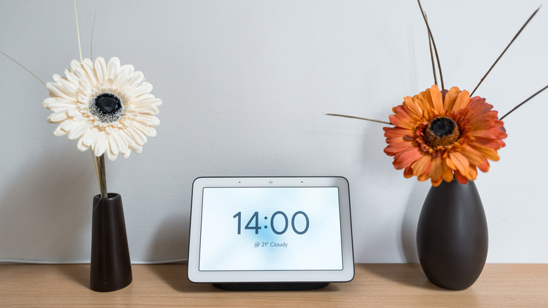 smart home tablet on table between two vases with flowers