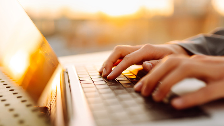 hands typing on a keyboard with sunlight on them