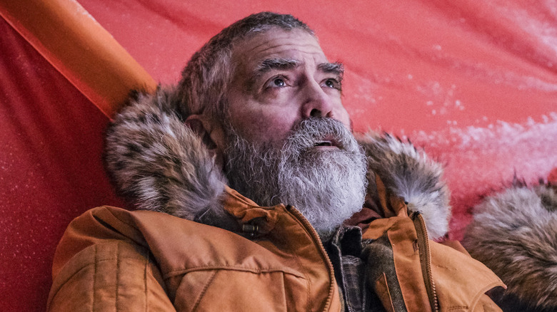 Augustine sitting against a red tarp in 