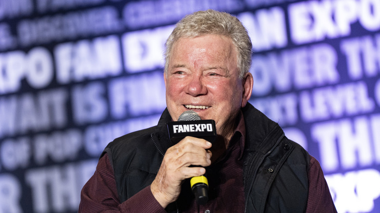 William Shatner smiling while holding a mic at FanExpo