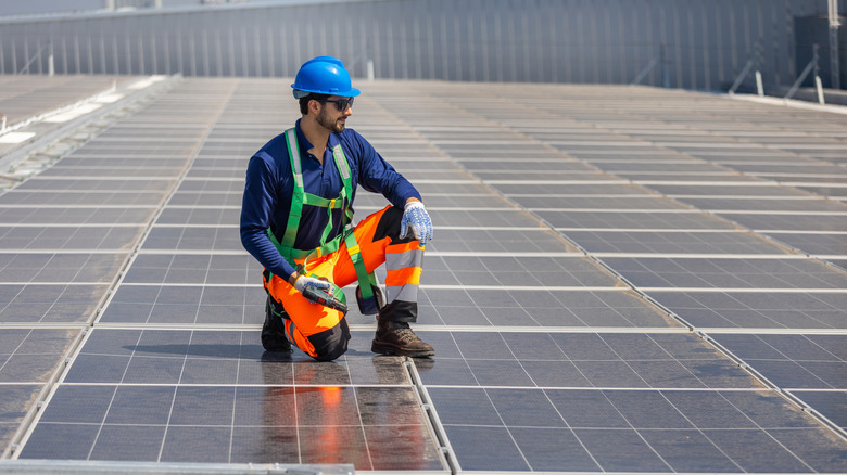 A solar panel technician working on a solar farm