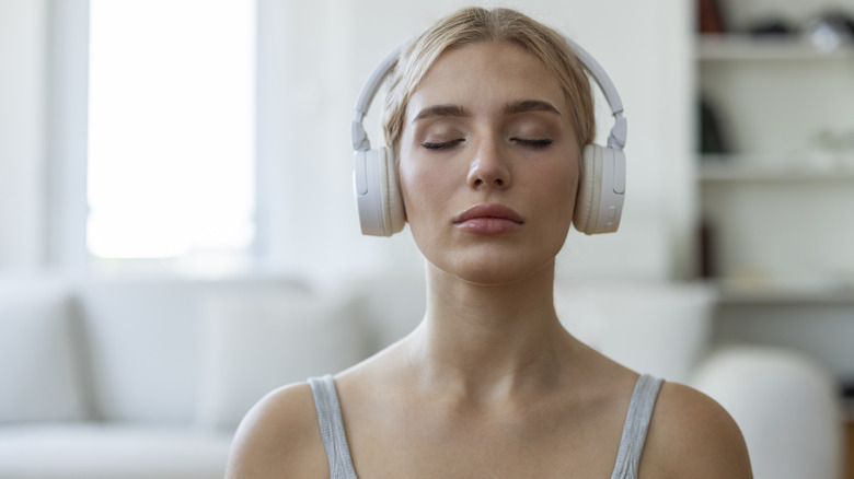 A woman with her eyes closed wearing white headphones