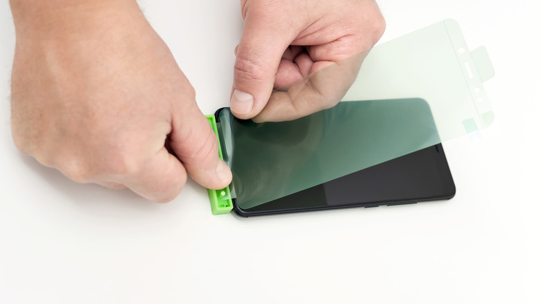 Person putting a hydrogel protector onto a phone.