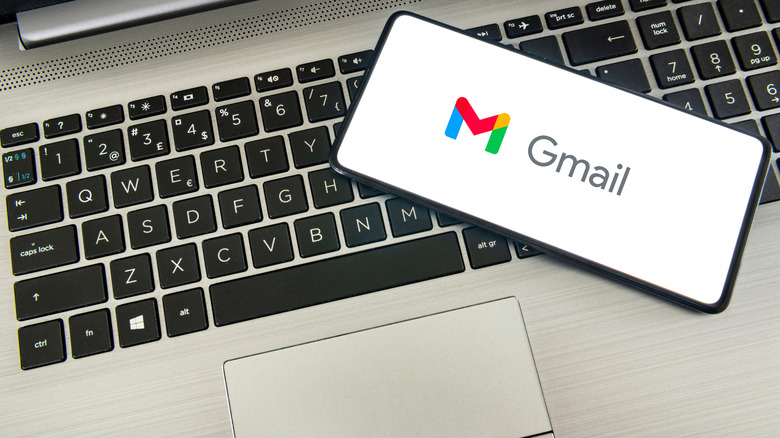 Gmail logo on a smartphone screen with a laptop underneath.