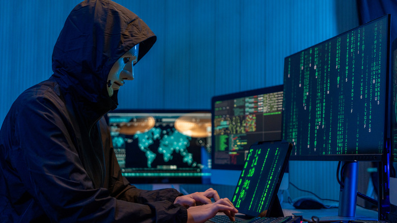 hacker using laptop to hack into a computer system, numbers scrolling on a monitor