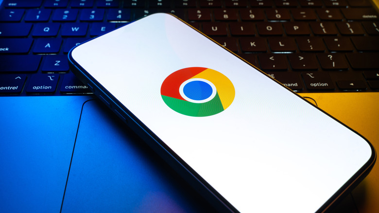 Google Chrome logo displayed on smartphone screen that's resting atop a keyboard.