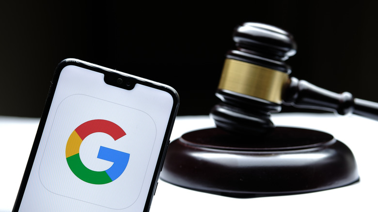 The Google logo displayed on a smartphone, with the phone placed in front of a gavel.