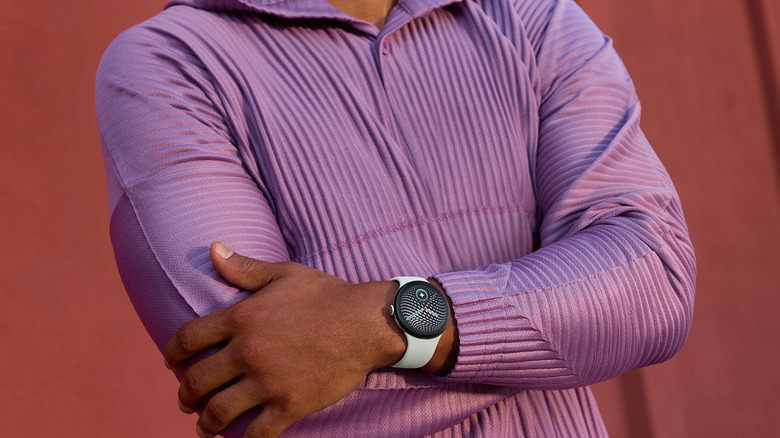 A man with his arms folded wearing a ribbed purple shirt and a Google Pixel Watch 5.