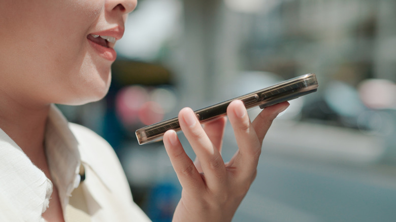 A closeup of a woman in a white shirt speaking into a cell phone