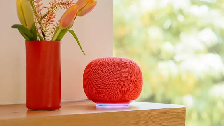 A new Google smart home speaker on a table beside flowers