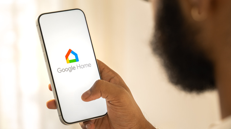 man holding smartphone with google home logo visible on it