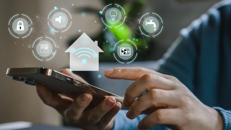 A person holding a smartphone with icons above it to represent a house and smart home devices