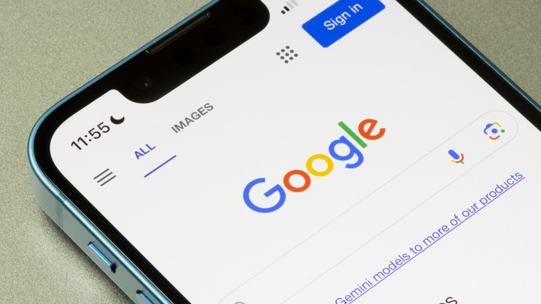 A blue smartphone sitting on its back displays the Google search home page