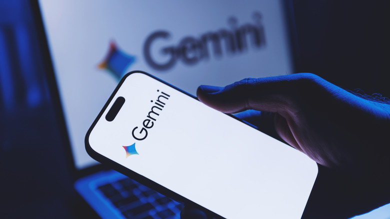 The Google Gemini logo seen on a smartphone in the foreground and a laptop in the background.