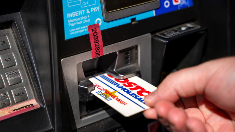 Costco card being used to pay for gas at station, held in hand