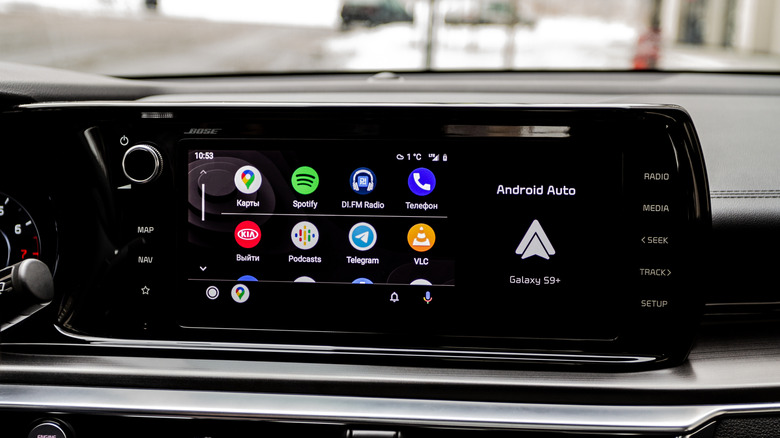A vehicle's dashboard with an infotainment screen displaying a grey Android Auto logo next to eight different Android apps