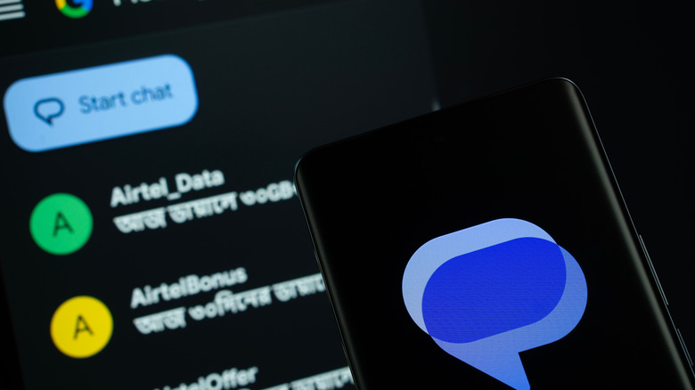 Google Messages logo on smartphone with messages showing in background