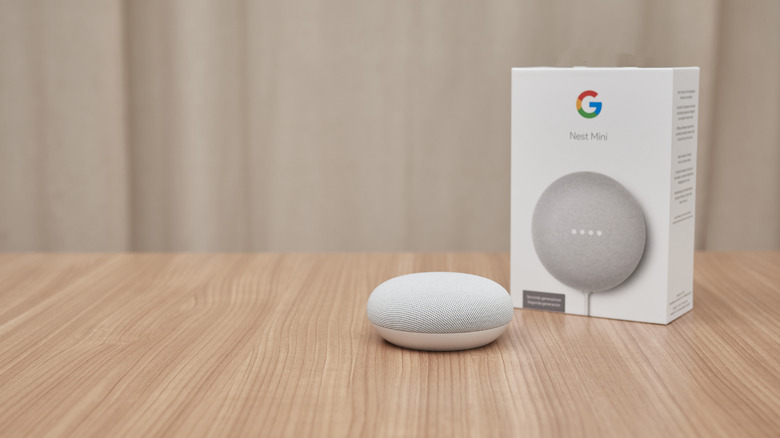 Google Nest Mini device sitting on table in front of box