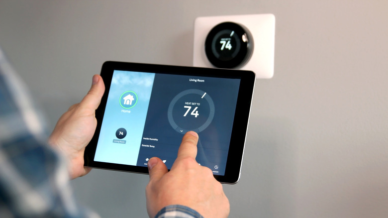 a man controlling his smart home thermostat through a tablet app