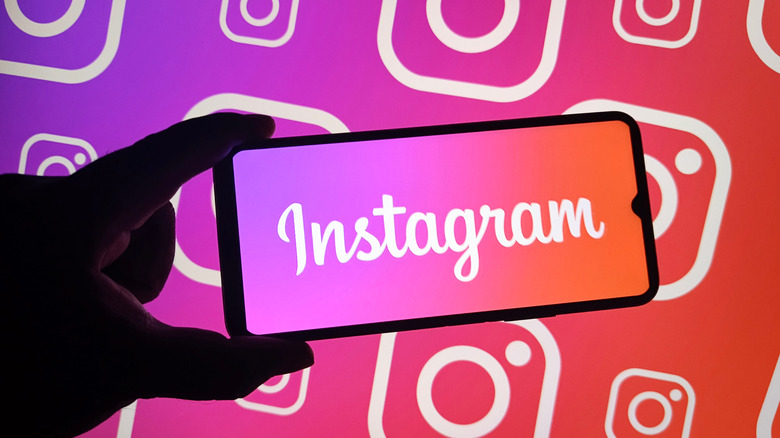 hand holding phone with instagram logo written out, logo on colorful background