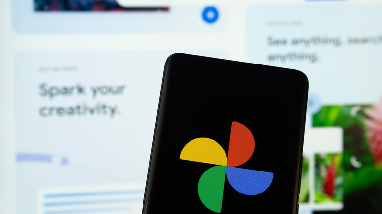 Google photos logo on a smartphone with advertisements in the background