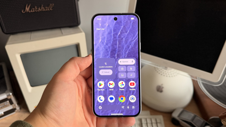 Pixel 11 with its display on being held in a hand