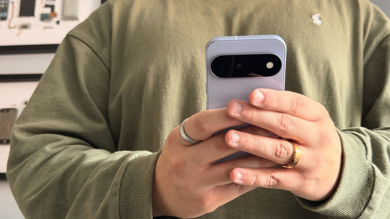 A person wearing a green shirt holding the Pixel 11