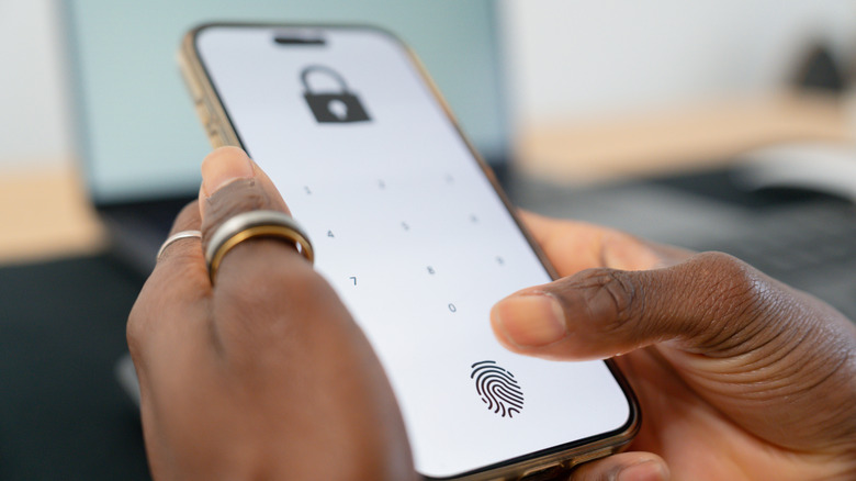 A person holding a phone that shows a lock on it screen with the option to add in a password or use a fingerprint to open it