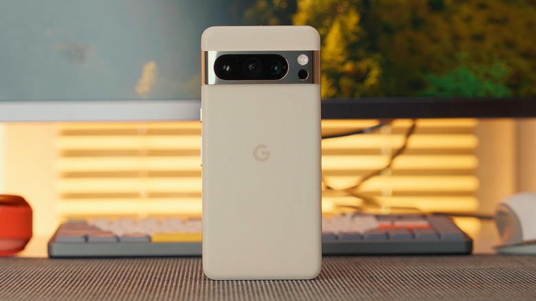 A white Google Pixel 8 smartphone sitting in front of a keyboard and some aesthetically pleasing lighting