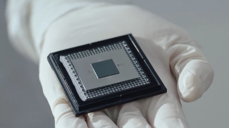A white gloved hand holds up Google's Willow quantum processing chip.