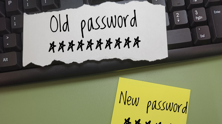 password written on a piece of paper resting on a keyboard, new password showing on another sticky note below it