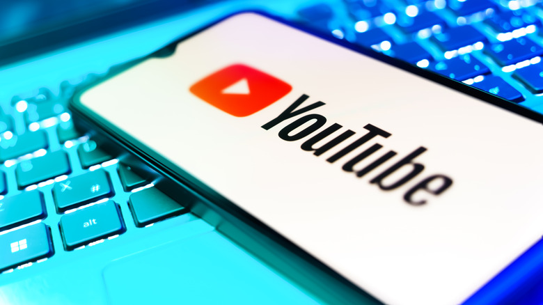 A smartphone on top of a laptop with the YouTube logo showing.
