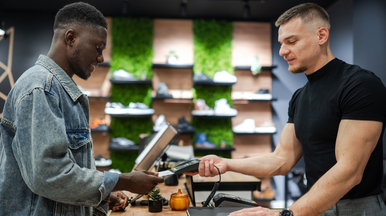 man buying a new pair of shoes, paying with his credit card