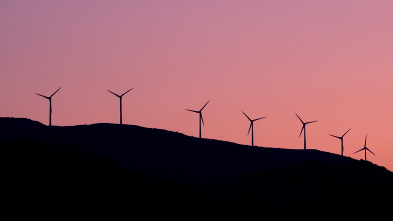 Wind turbines on a hill in Greece at sunset.