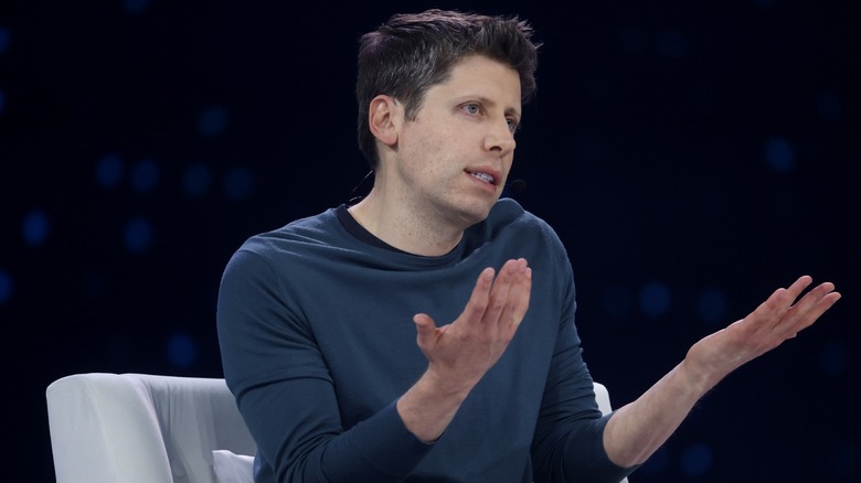 Sam altman shrugging while on stage at an OpenAI presentation
