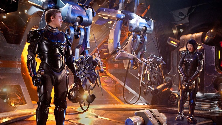 Two Jaeger pilots standing in front of a giant robot in 