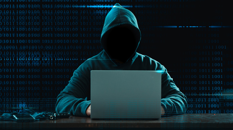 concept image of a hacker at computer in the dark