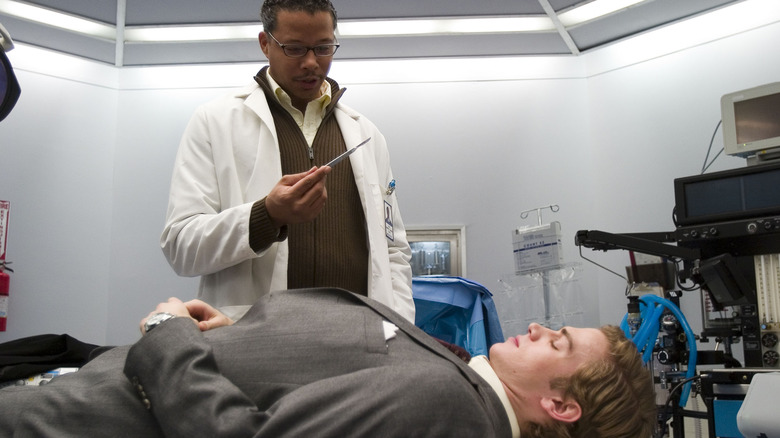 Dr. Harper holding a scalpel over Clay laying on the operating table