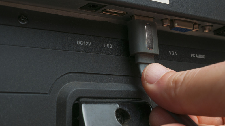 Someone plugging an HDMI cable into a display.