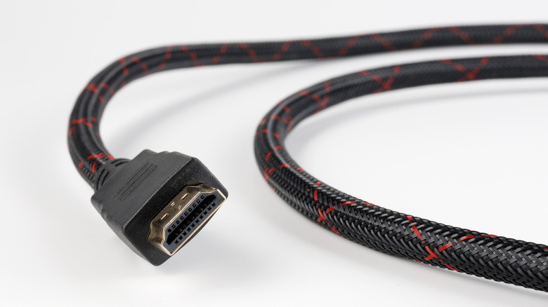 A photograph of an HDMI cable on a white background. The cable has a braided black and red cord.