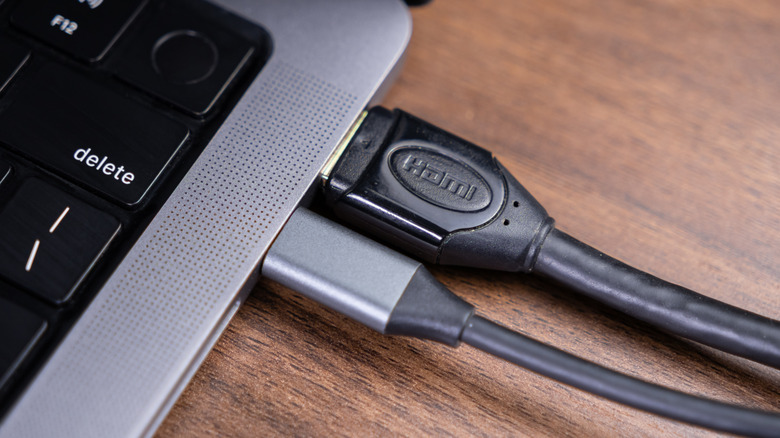 A USB-C and HDMI cable plugged into the side of a MacBook Pro