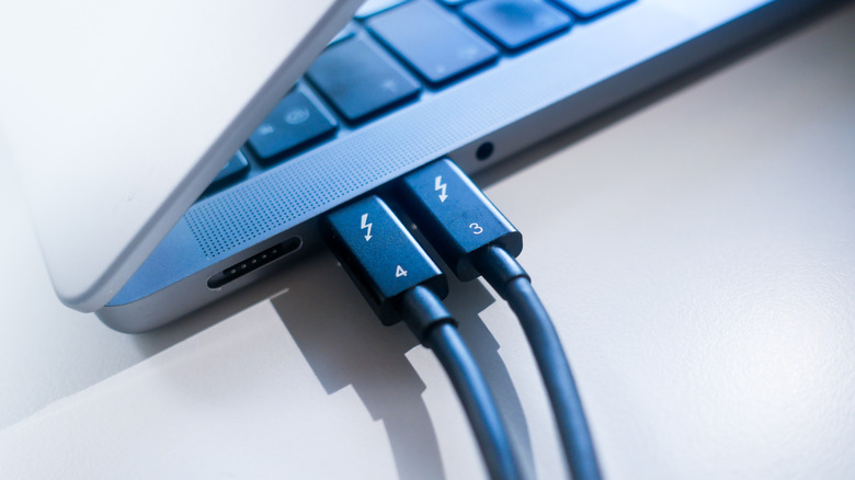 Two versions of Thunderbolt cables plugged into a MacBook pro