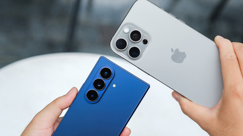 A Samsung Z Fold 7 and iPhone 16 Pro being held next to each other